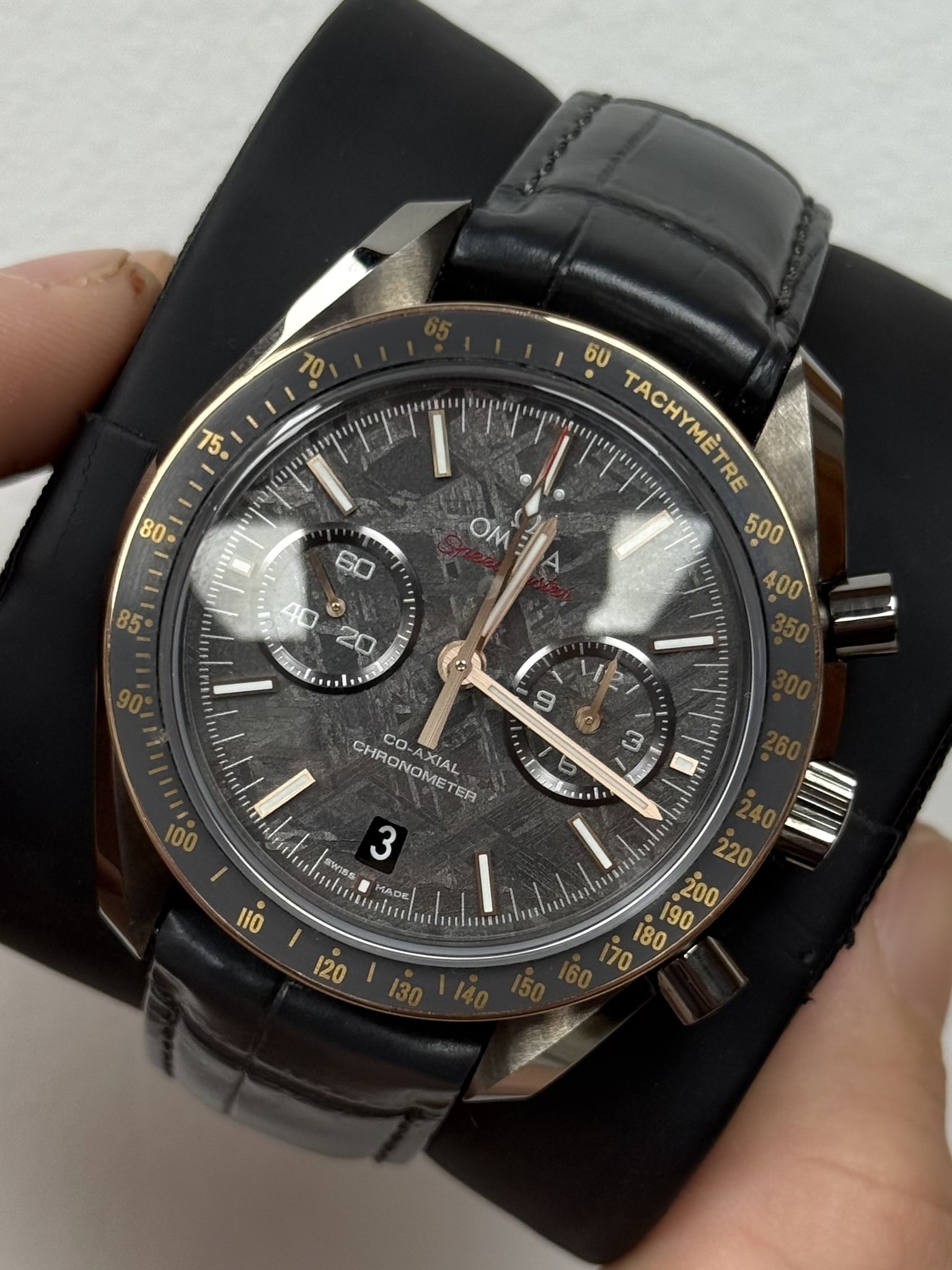 May be an image of wrist watch and text that says '10 5 80 OM 60 60 TACHYMÈTRE E 9 (c) W 100 真い CHRONOMETER TER CO- CO-AXIAL AXIAL sureds SW美S 3 e/T 不者 MADE 11O '