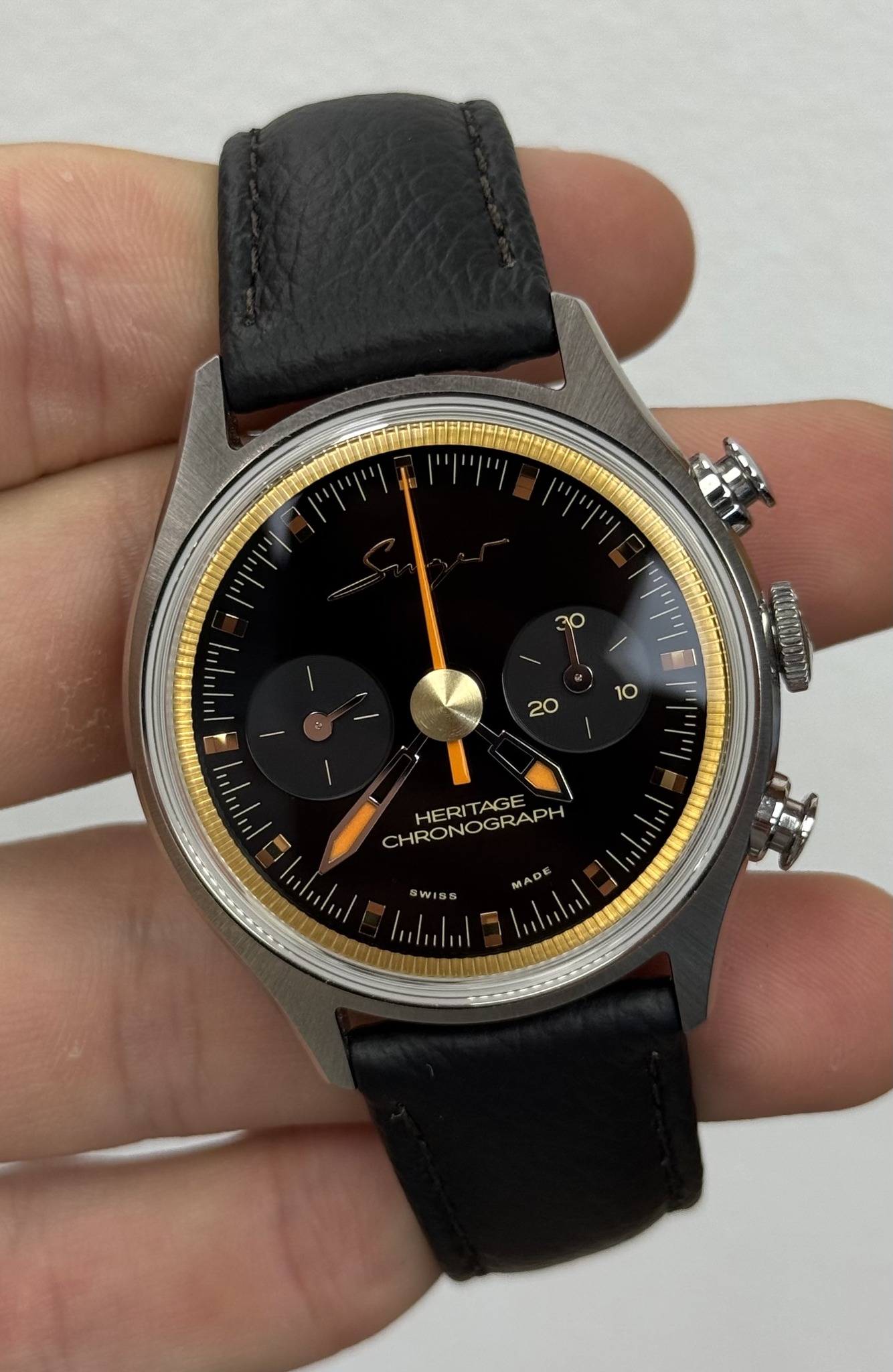 May be an image of ‎wrist watch and ‎text that says '‎እጥ T' ["/ የዮት'ዮማ וייוי וייוייןי แุท 30 د 10 20 ロ CHRONOGRAPH HE HERITAGE MADE WISS rp‎'‎‎