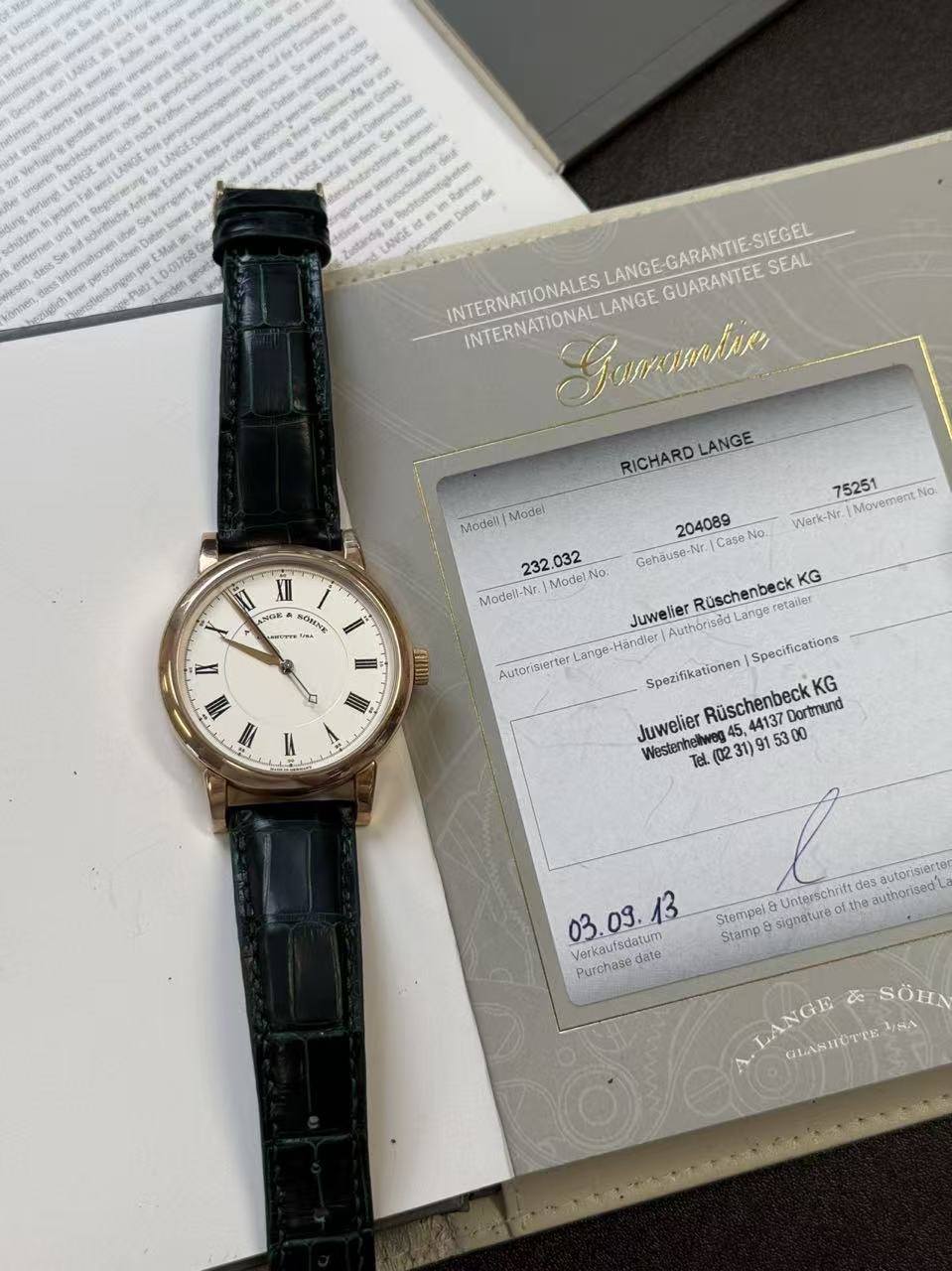 May be an image of wrist watch and text that says 'schesstreit Daten INTERNATIONALES ALESLANGE-GARANTIE-SIEGEL LANGE GARANTIE-S SIEGEL INTERNATIONAL KeHuTypTKuK LANGE GUARANTEE…