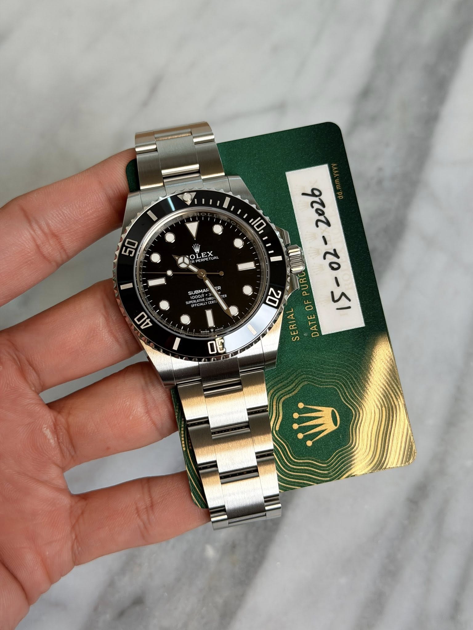 May be an image of wrist watch and text that says 'I 50 10 OLEX OL LE SUBMAR MAI 40 2026 URO 20 OF 15-02- SERIAL DATE 0E'