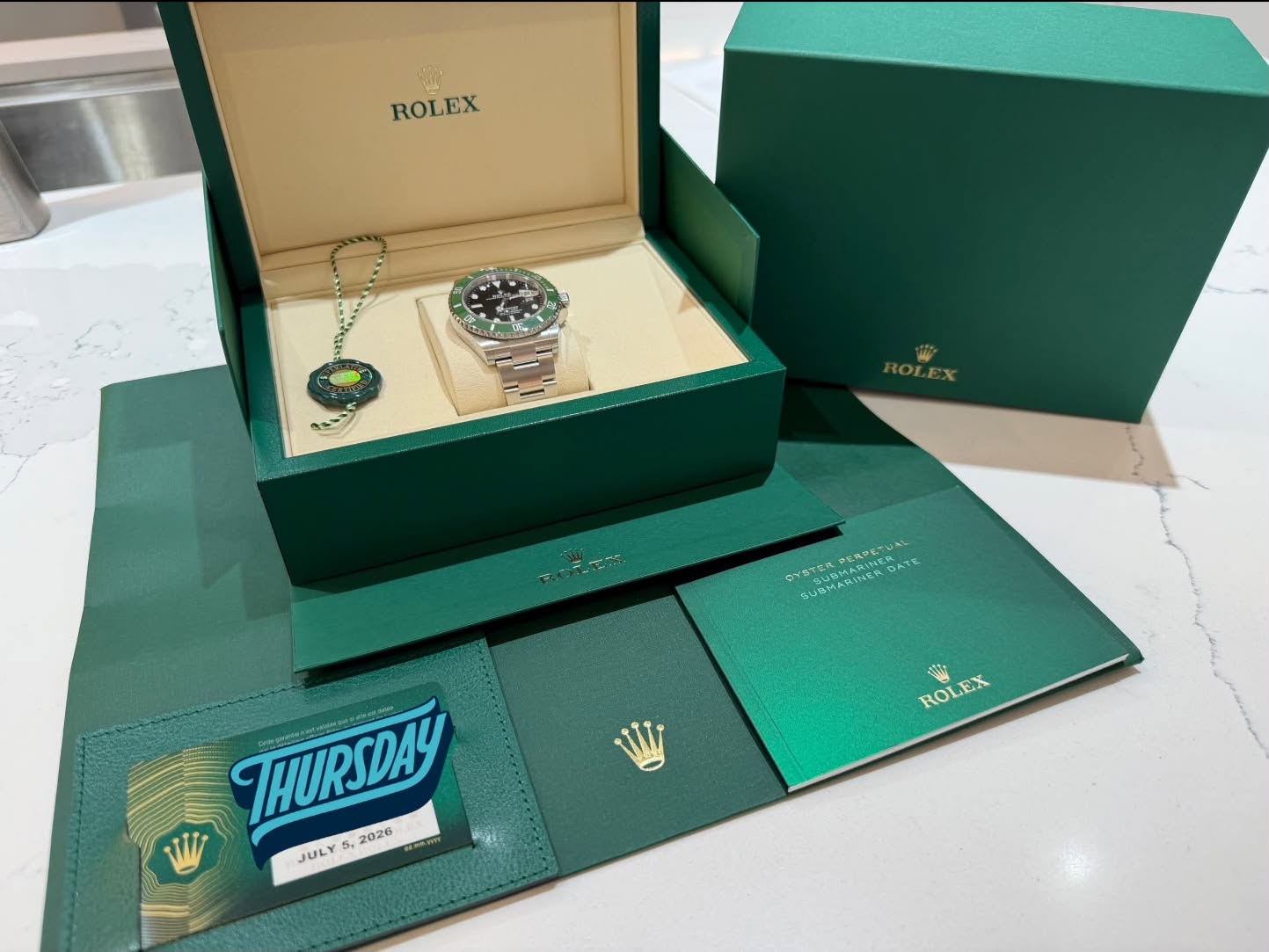 May be an image of wrist watch and text that says 'ROLEX Ora SUBMARINER 3すさ列 あ CUSMARIN AE た 6 ROL EX ROLEX S THURSDAY 2026 W JULY 5y 5.2'