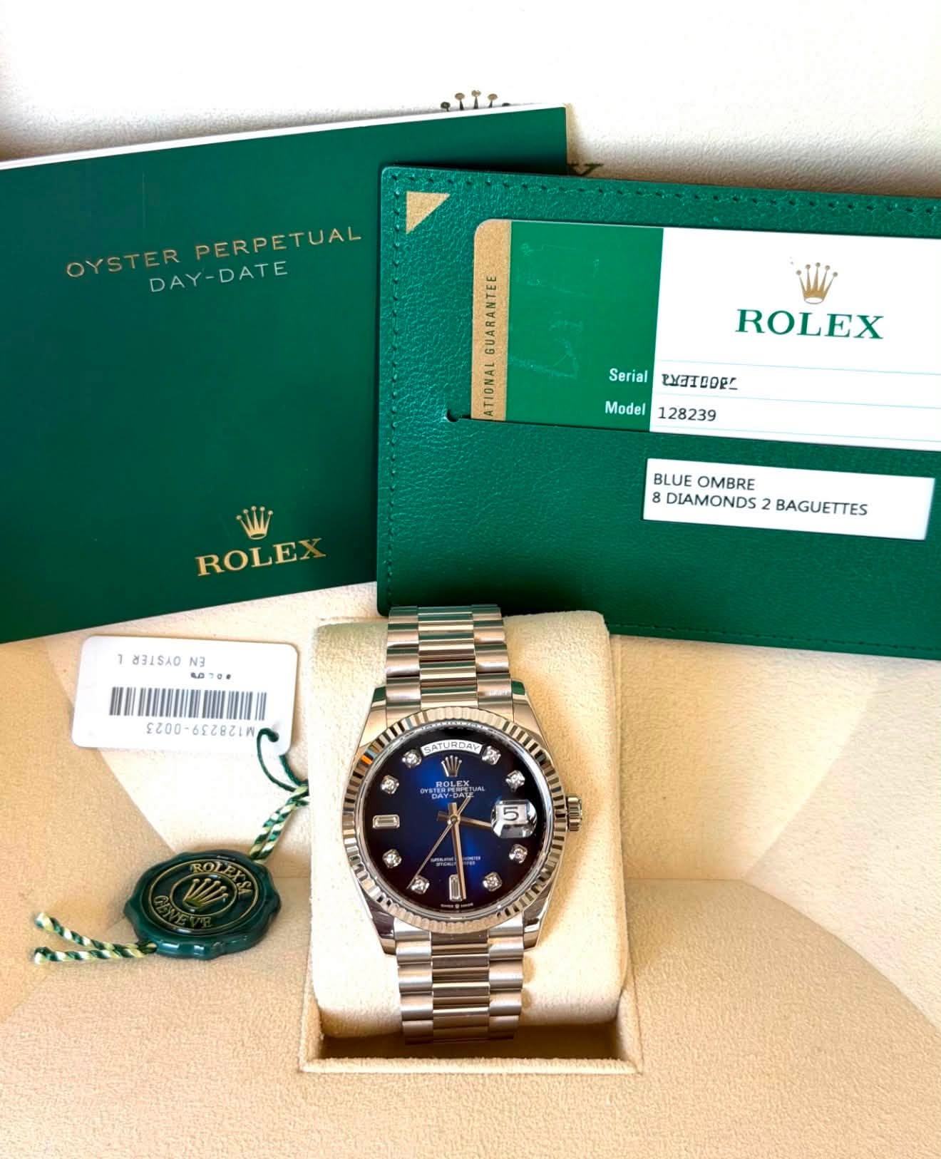 May be an image of wrist watch and text that says 'للله OYSTER PERPETUAL DAY-DATE 12 ROLEX Serial WGIDORC Model 128239 ROLEX BLUE OMBRE 8DIAMONDS2BAGUETTES 8 DIAMONDS BAGUETTES…