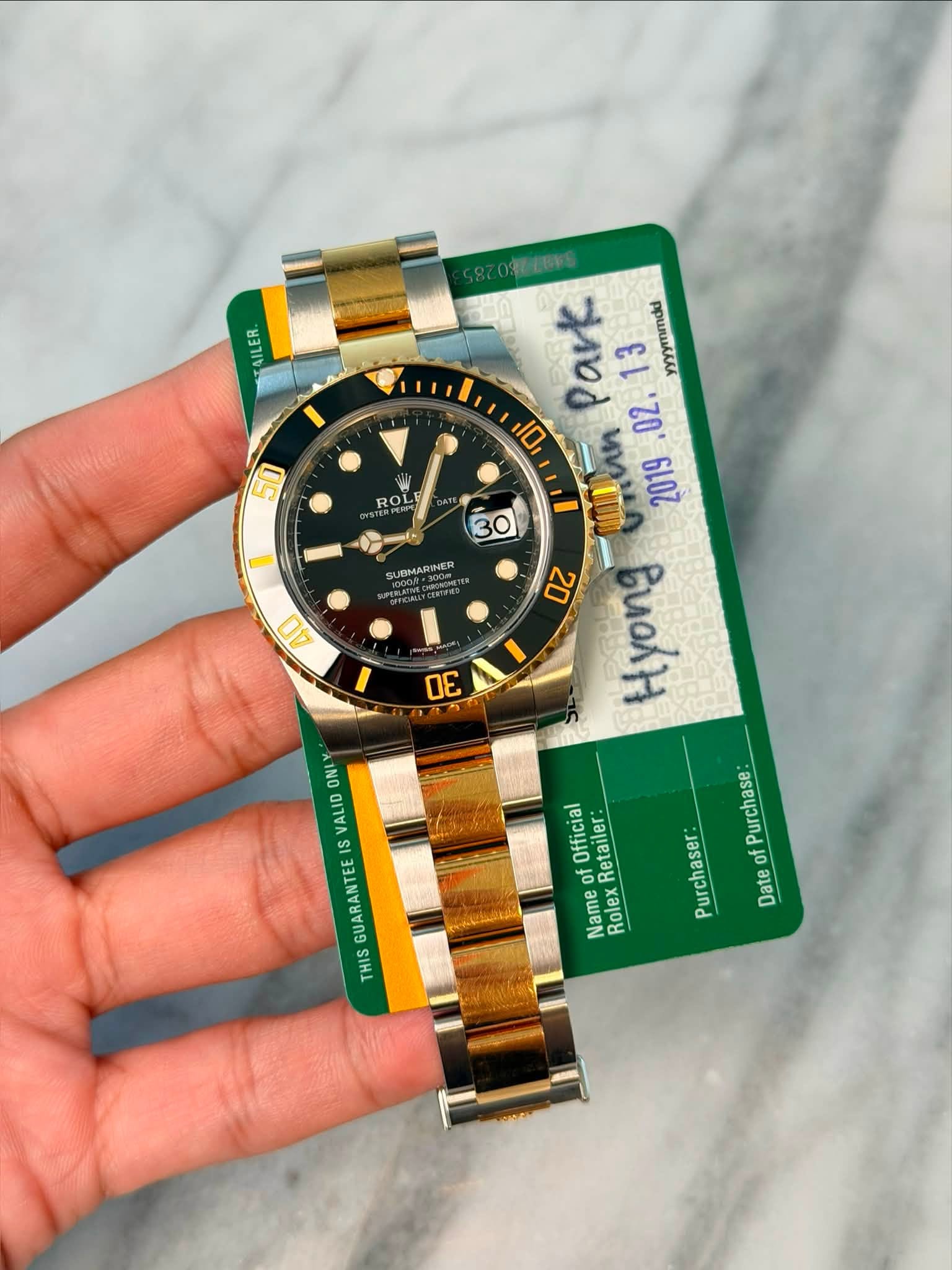 May be an image of wrist watch and text that says '50 ROL O8E2UNG Park 13 yyyymmdul D 02. 30 mlan 2019 20 uoH SUEMARINEN 4υ D0 ONLY VALID IS Official Retailer: Name Rolex Purchase…
