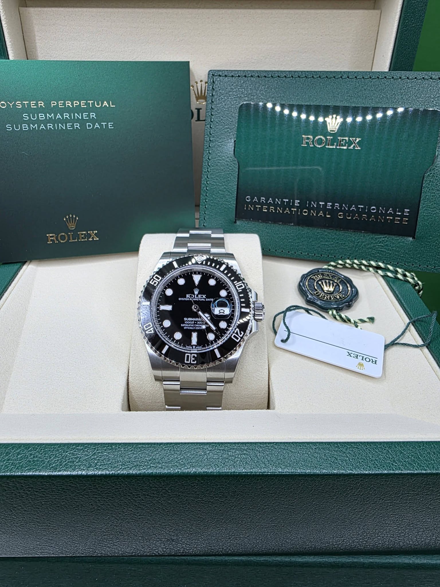 May be an image of wrist watch and text that says 'OYSTER PERPETUAL SUBMARINER SUBMARINER DATE ROLEX RV GARANTIE IIGRNATION INTERNATIONALGU INTERNATIO 50 10 COLEX PLF LE BATE In 8…