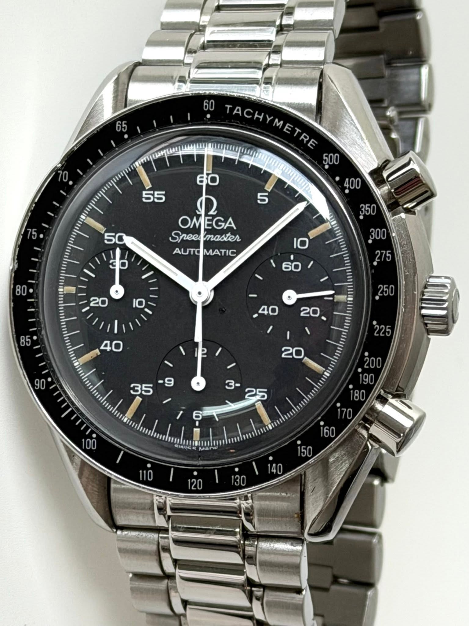 May be an image of wrist watch and text that says 'TACHYMETRE TACH METRE OMEGA Speecmaster Spee master AUTOMATIC AUTO MATIC '