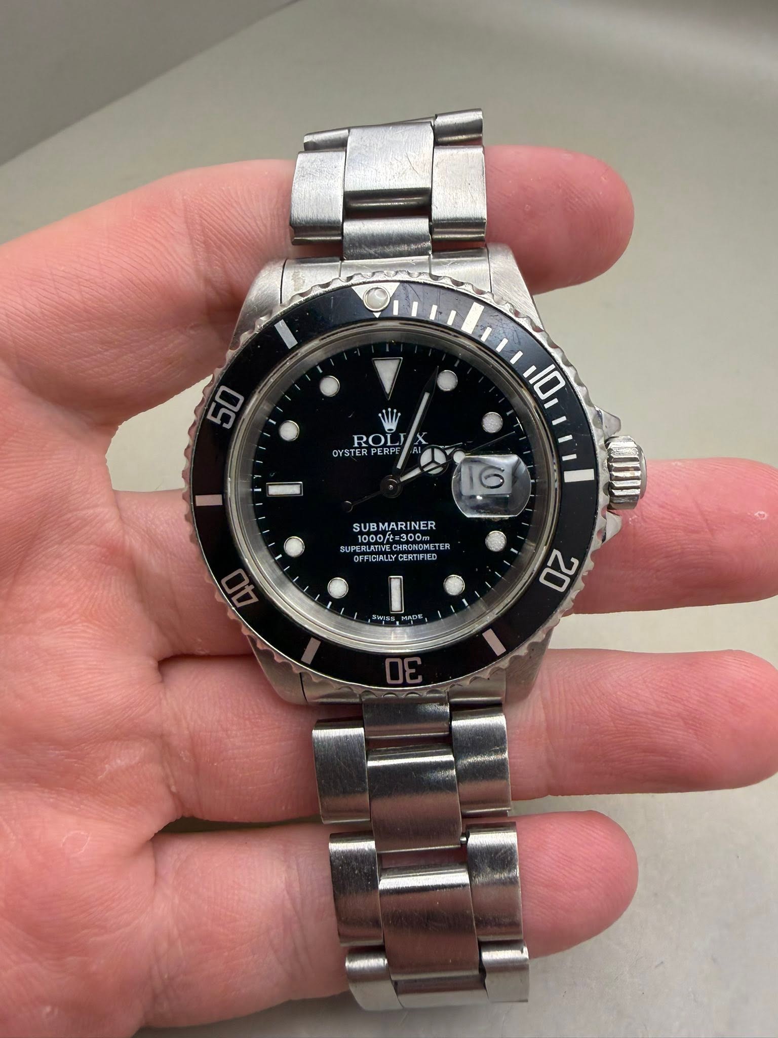 May be an image of wrist watch and text that says '50 ROL YSTER PE 10 16 SUB SUBMARINER 1000ft=300m 300T EMATE 10001 FFICIALLYCERTIFI CERTIFIED I 20'