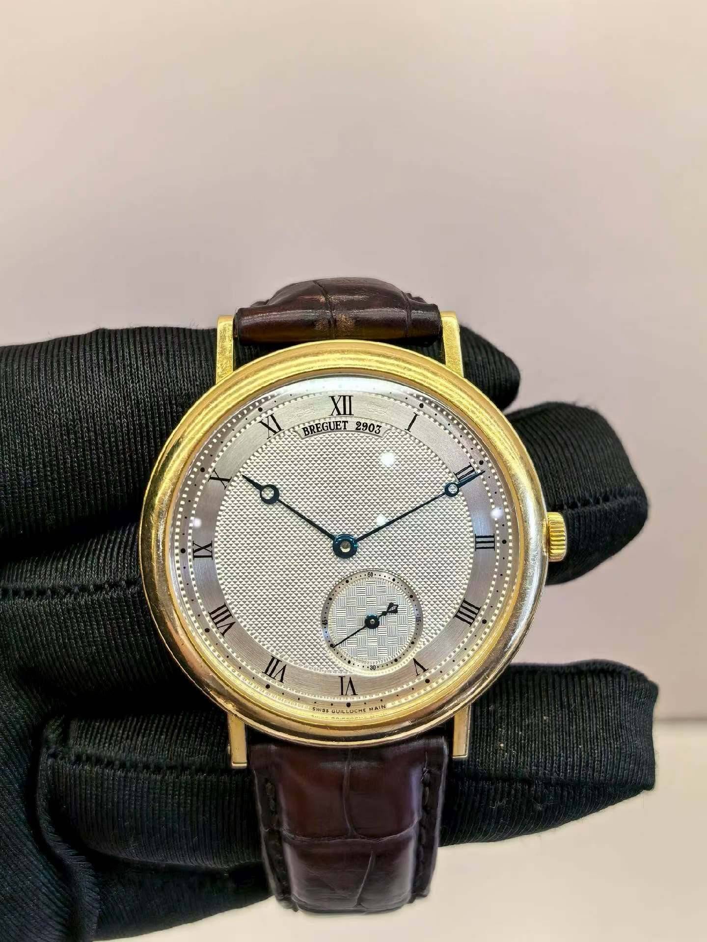 May be an image of wrist watch and text that says 'XII BREGUET BREGUET_2903 2903 MJE URLUCHS'