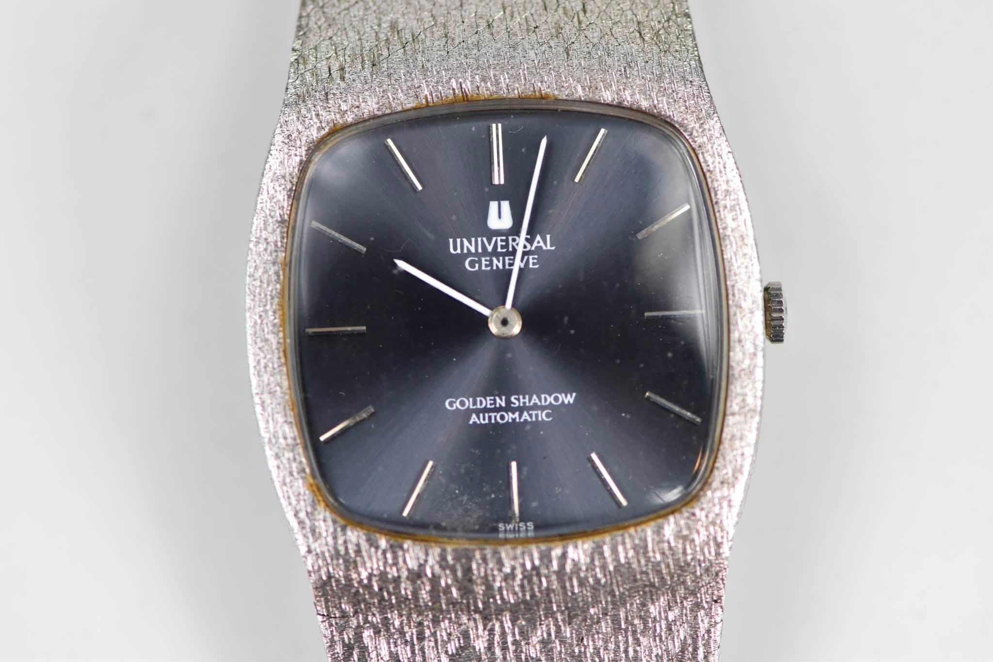 May be an image of digital watch and text that says 'l/' UNIVERSAL GENEE J85L10U GOLDENSHADOW GOLDEN SHADOW AUTOMATIC SWISS'