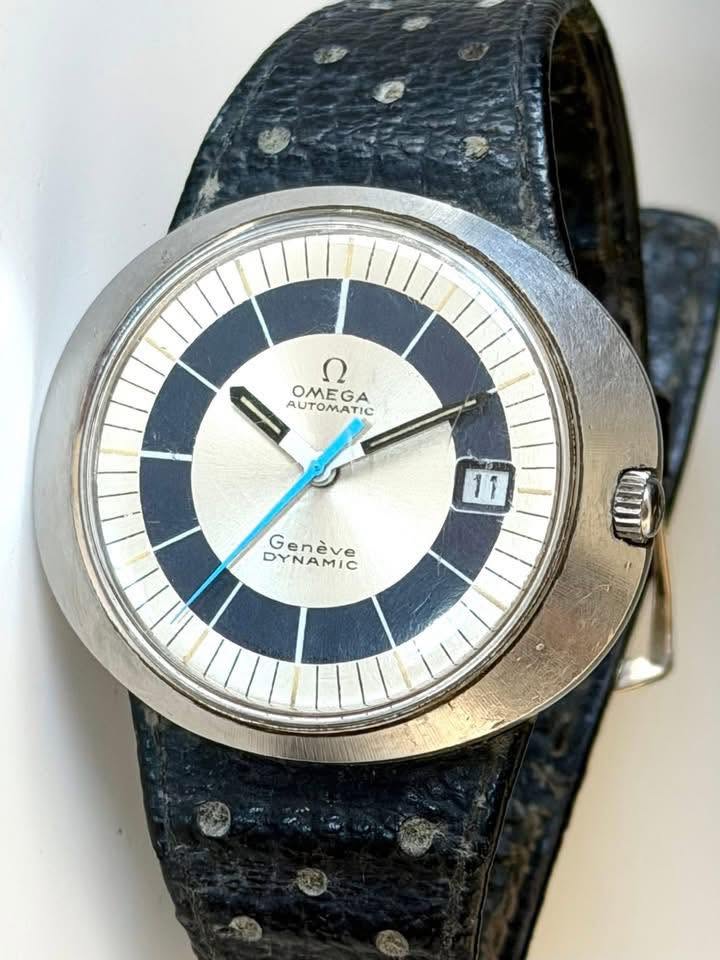 May be an image of leather, wrist watch and text that says 'ع OMEGA AUTOMATIC 11 DYNAMIC Genéve OIDI'