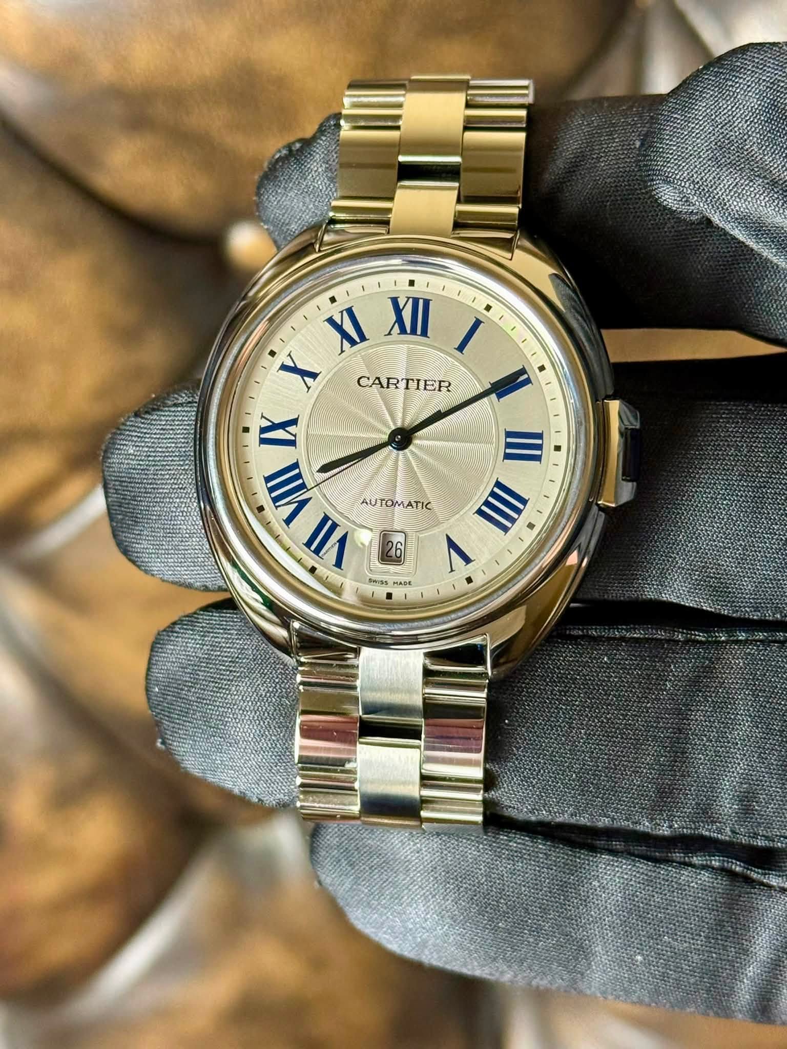 May be an image of wrist watch and text that says 'XI XII I X CARTIER IX W IIVIII AUTOMATIC AUTOMATIC VIIII III VII 26 V ۱ Sass ቤስኑ MADE'