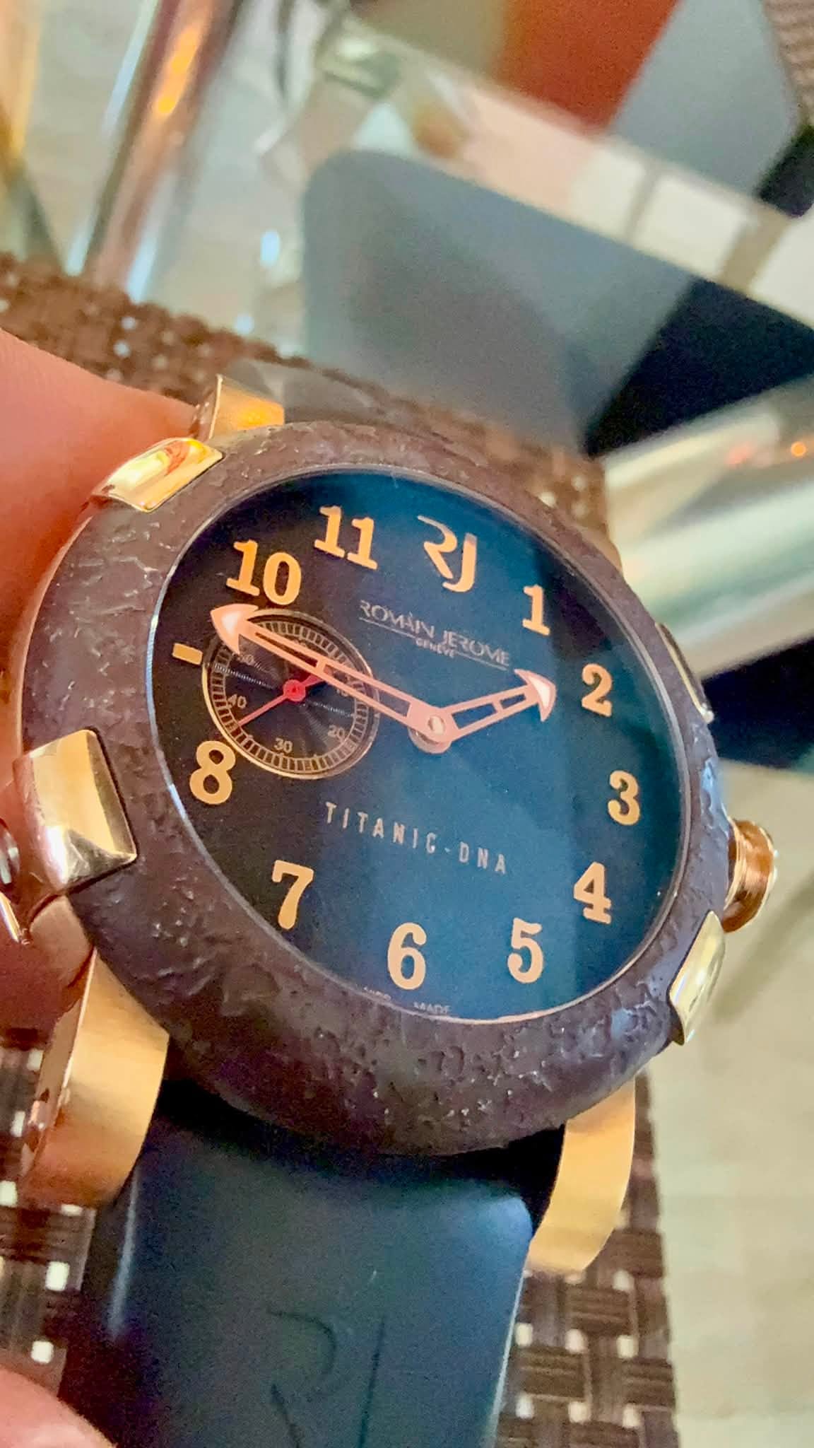 May be an image of wrist watch and text that says '10 11 112J RJ ICLIXCO ROMINERUME 1 ROMAN SENEVE र JERUME TITANIG-ONA '