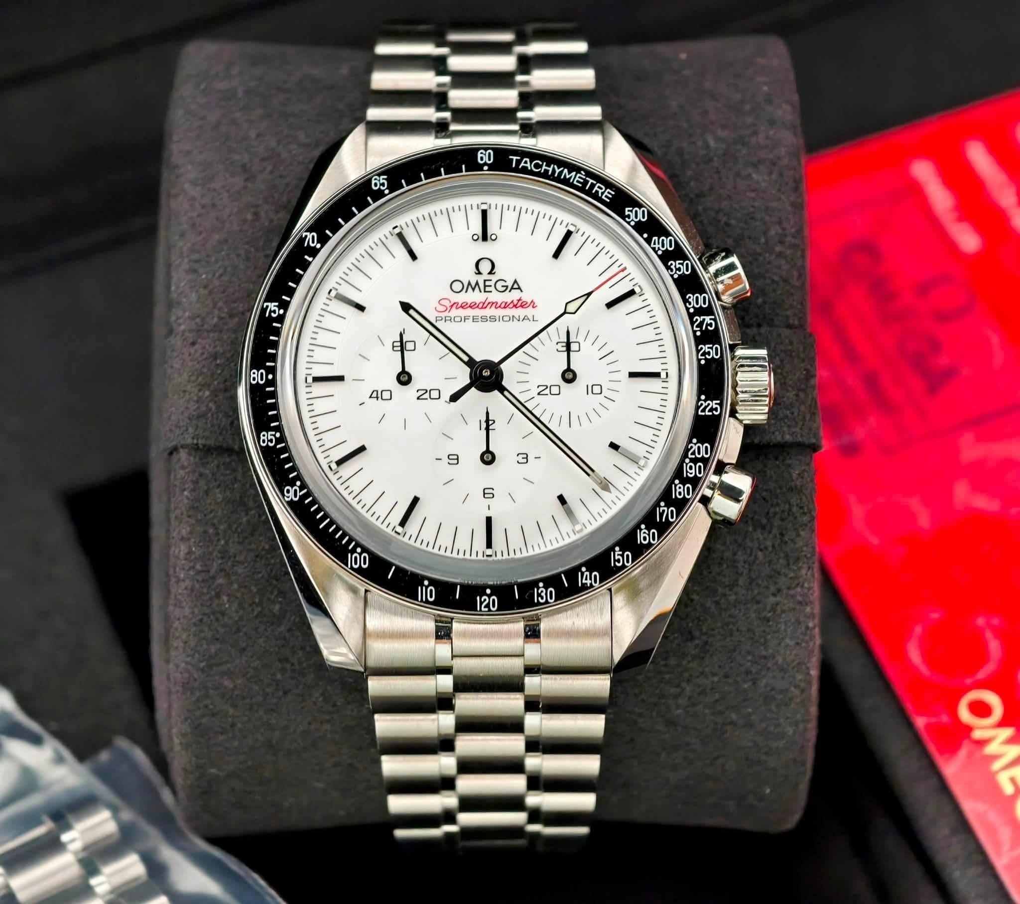 May be an image of wrist watch and text that says '65 በ2 60 TACHYMETRE 500 400 lo ي Sneedmaster கன OMEGA . ه I 9 < ào io 30 ه OML'
