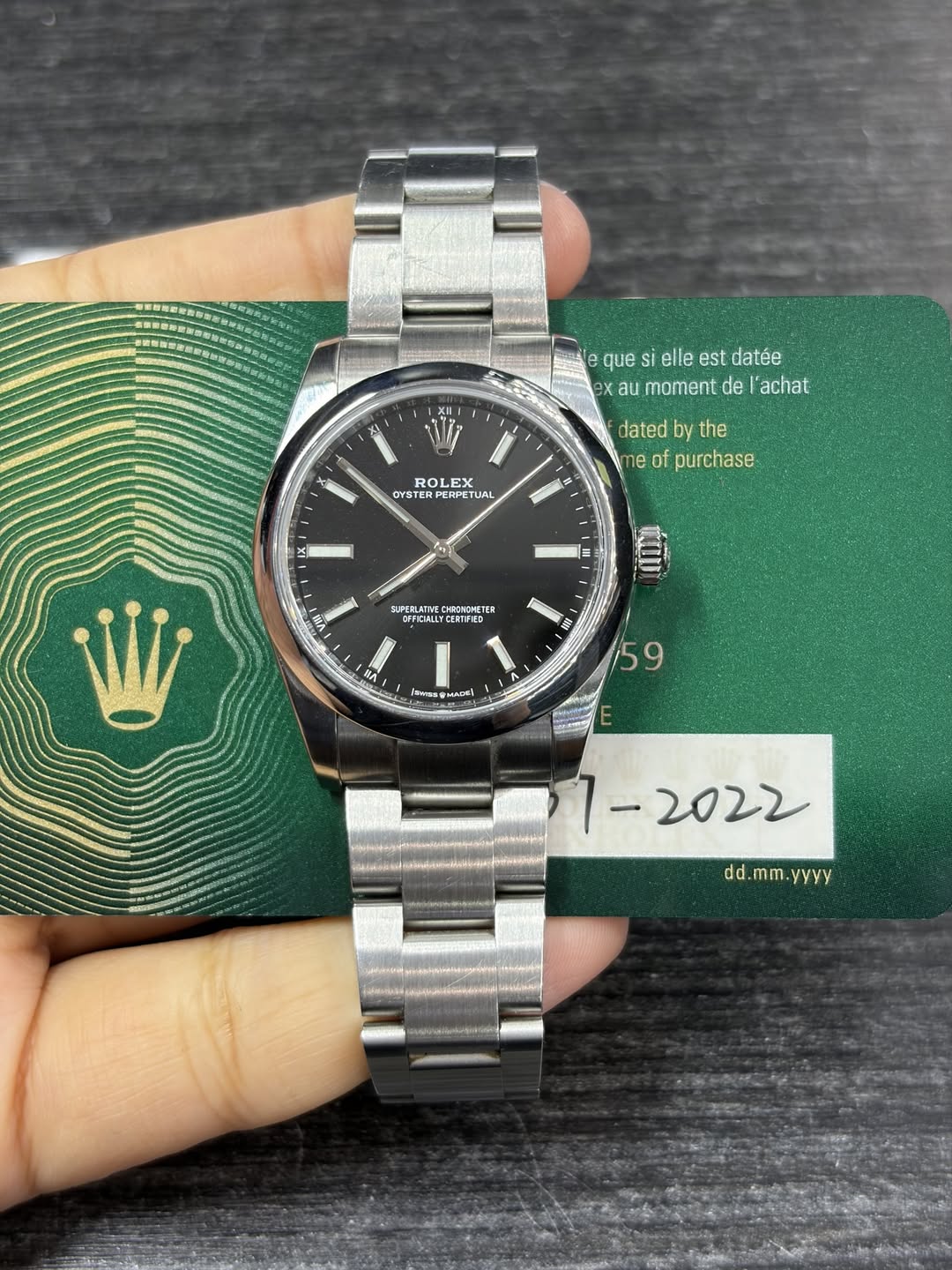 May be an image of wrist watch and text that says 'Ne que elle est datée eX X au moment de l'achat ROLEX OYST OYSTERP STERPERE ERETUAL TUAL dated by the me of purchase 수 送 II VB…