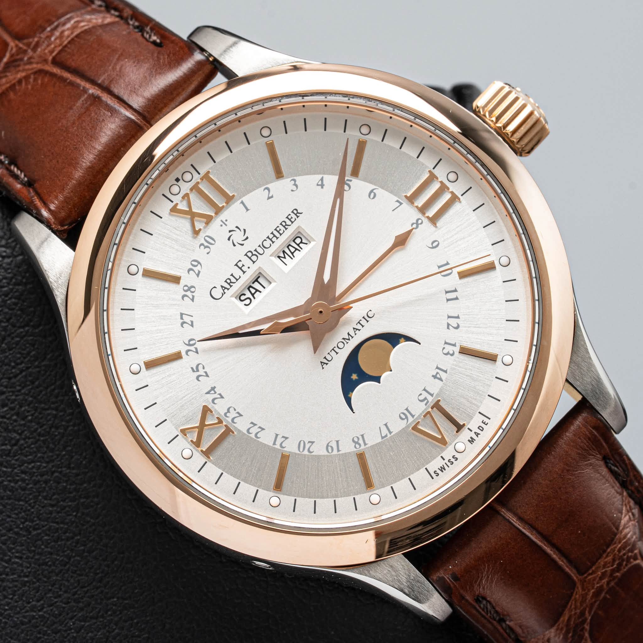 May be an image of wrist watch and text that says 'መ 5 6 7 7 IIII XH 3 4 30 中 に BUCHERER MARI 28 29 CARL F SATI o ك AUTOMATIC II 21 ει ቀ SL 12 00 6L LI VI swissOMADEl SWISS…
