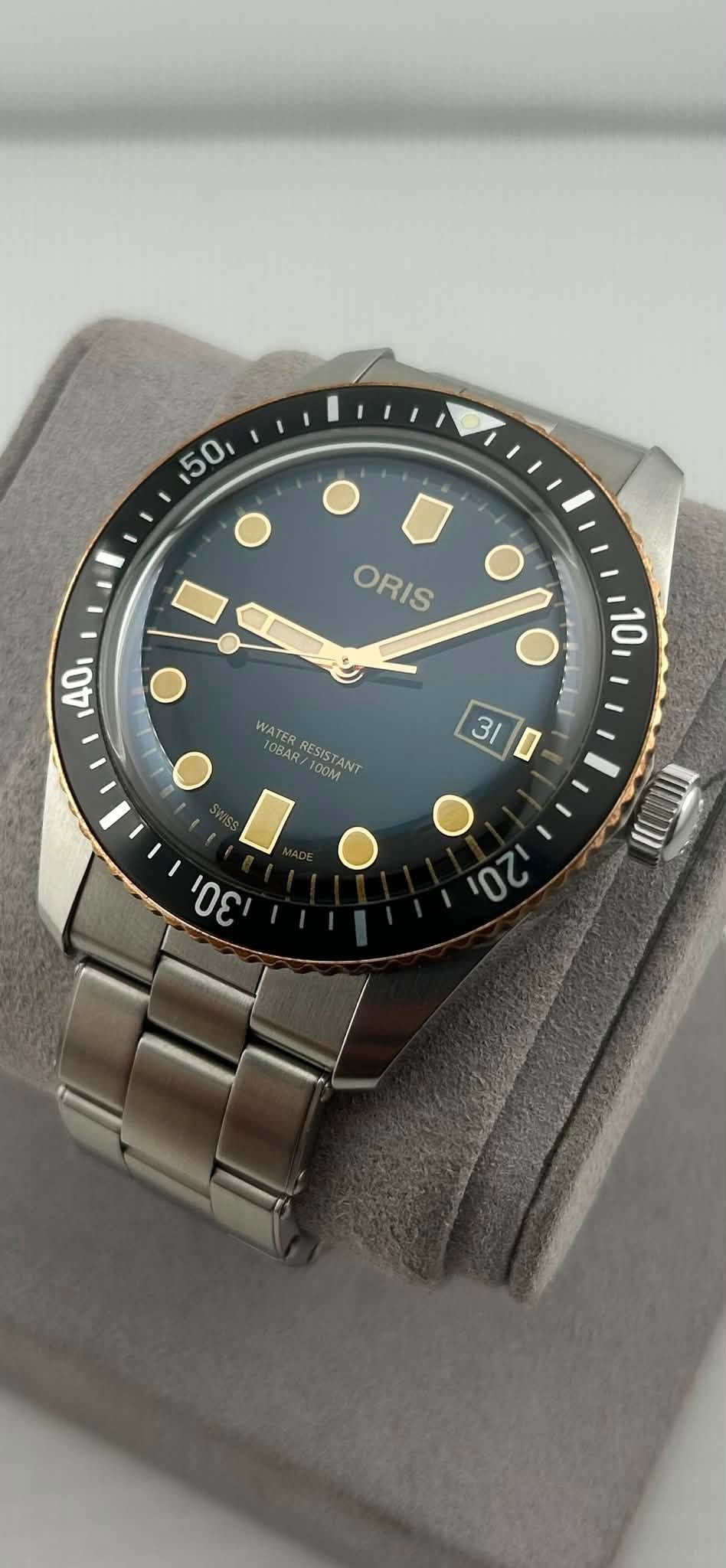 May be an image of wrist watch and text that says '50 0 ORIS ORIS 40 10 31 WATER IOSA0 10BAR/ RESISTANT RESIST I 100M פט U 20'