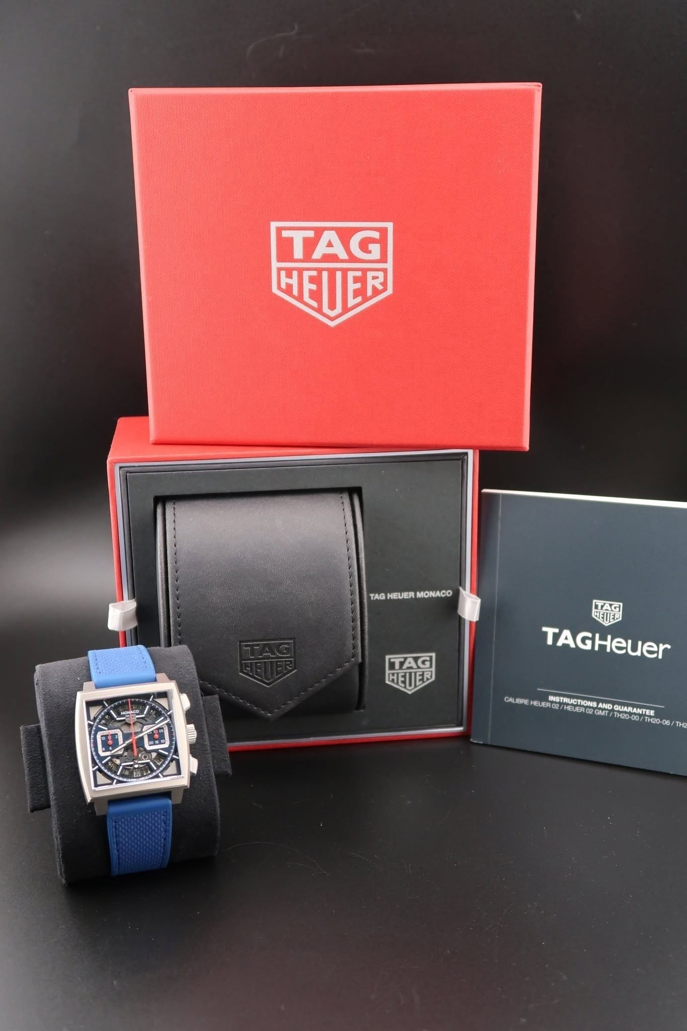 May be an image of digital watch and text that says 'TAG HETER τAA HEUER TAGHEUERMONACO MONACO KAG 生袋 TAGHeuer TAG HEUE CALAR CLRECLC DMT TH20-00/ INSTRUCTIONS ND GUARANTER 海网'