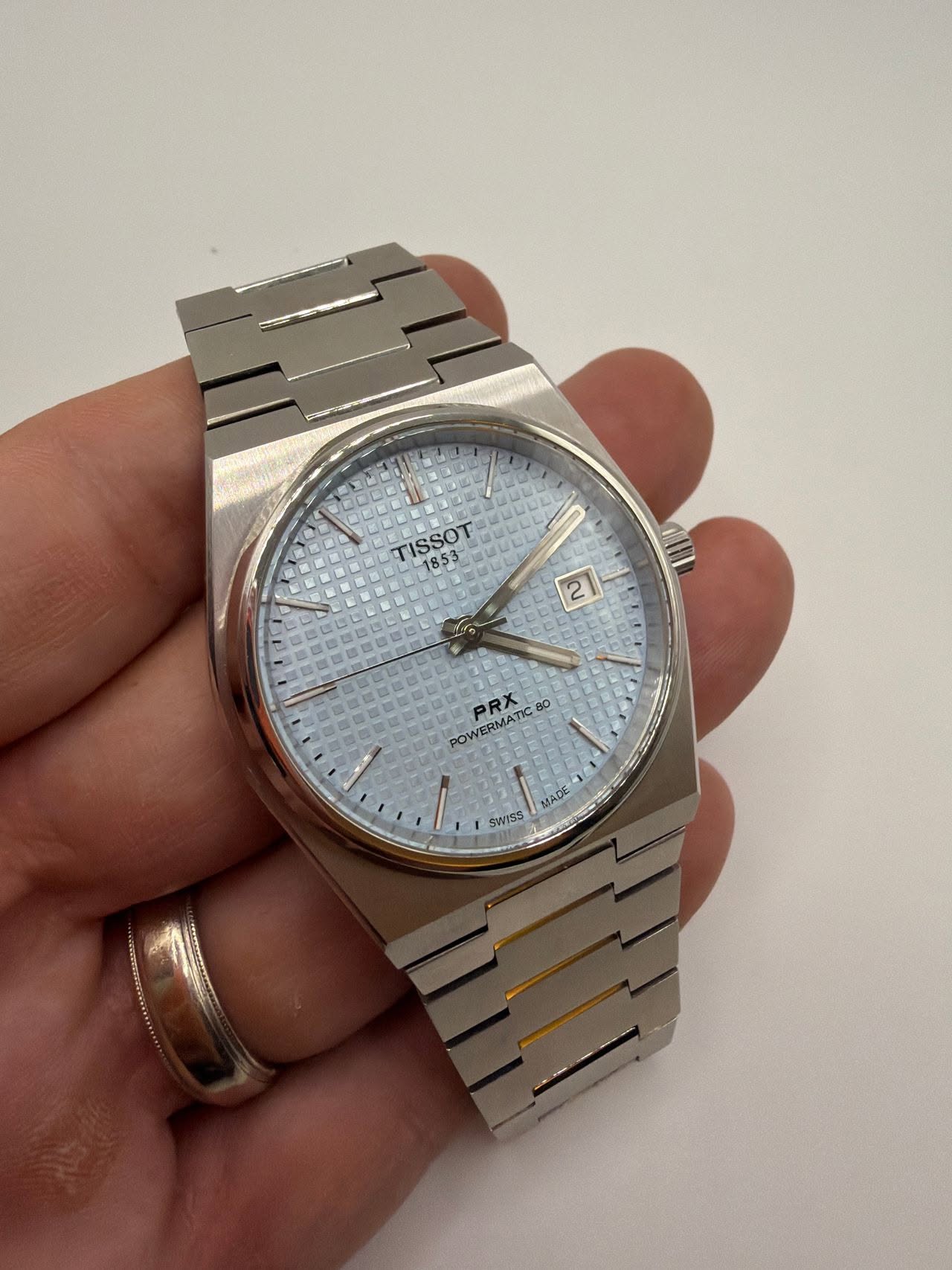 May be an image of wrist watch and text that says 'TISSOT L- NUEE PRX POWERMATIC8O SN 속 MADE SWYSS'