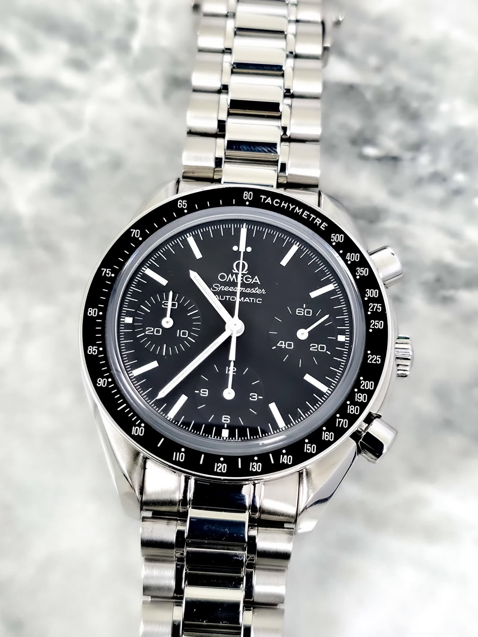 May be an image of wrist watch and text that says ' TACHYMETRE TACHYMETD ם OMEGA OM GA Speenmaster master Speea UTO JTOMATIC ATIC P 9 1 3- 0i an '
